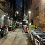 a narrow alley with trash cans and garbage cans