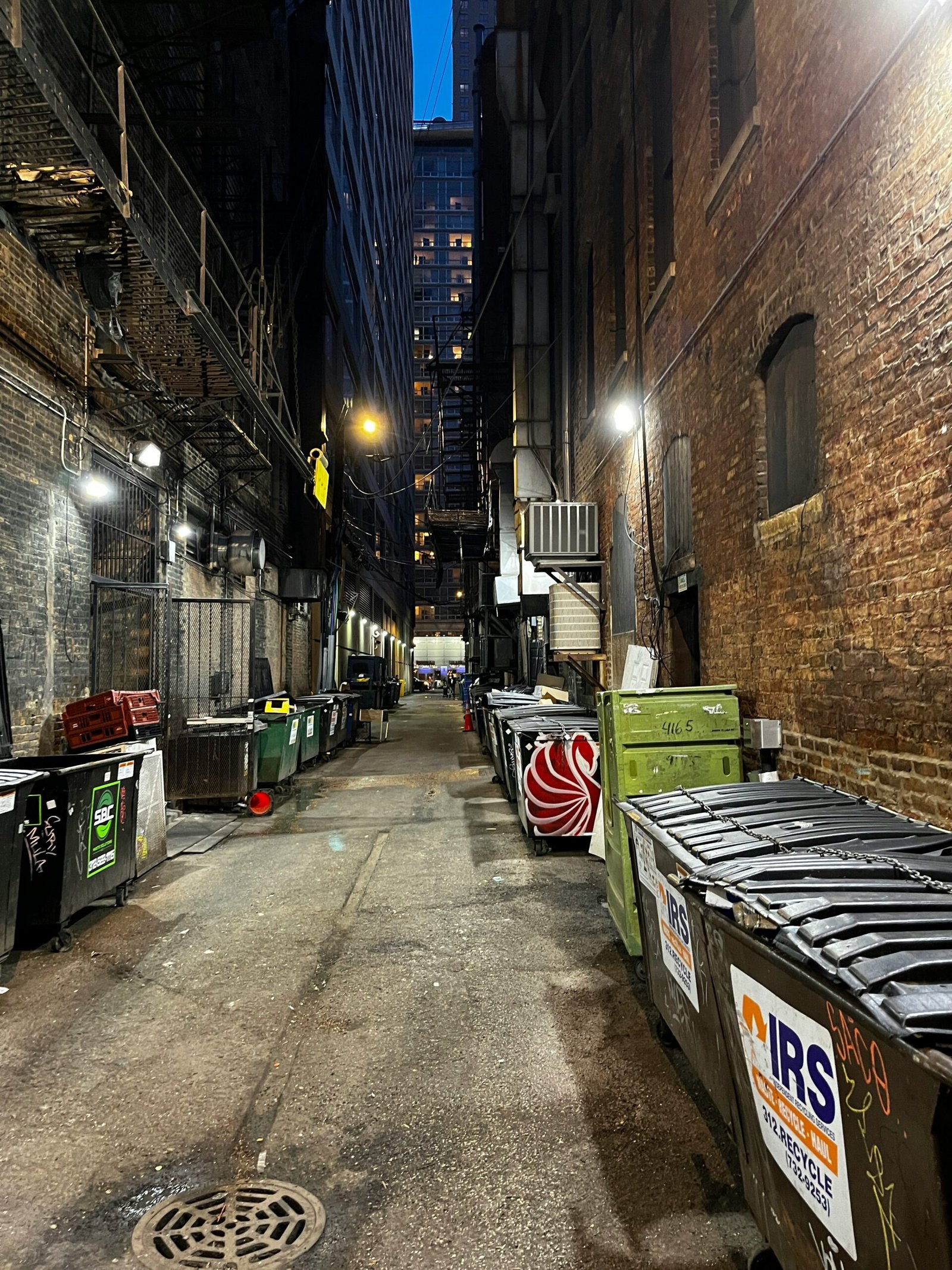 a narrow alley with trash cans and garbage cans